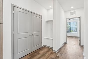 A white hallway with a wooden floor and two white doors.